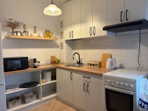 una cucina con mobili bianchi, un lavello e una stufa di ZMC Apartment a Orăştie Altre 22 foto