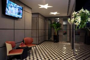 ein Wartezimmer mit Stühlen und einem TV an der Wand in der Unterkunft Hotel 81 Premier Hollywood in Singapur