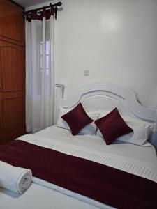 a large white bed with two red pillows on it at Glome Stays in Kisumu +2 photos