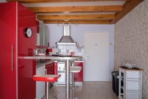 a kitchen with red cabinets and a red stool at Calme et confort en Charente , Gîte Les Vignes avec piscine in Saint-Médard