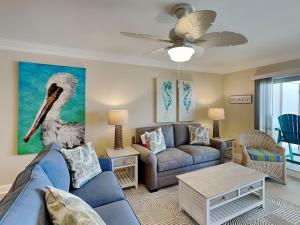 a living room with a blue couch and a bird painting on the wall at Regency Towers #505 West in Oriole Beach