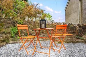 Dos sillas naranjas y una mesa con una licuadora encima. en 6 Bed Family Home With Free Parking, en Swansea