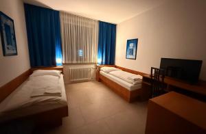 a room with two beds and a window with blue curtains at Hotel G&K in Giesen