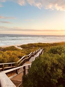 ウィルダネスにあるDe Schuit Beach Houseの海のあるビーチに続く木製の遊歩道
