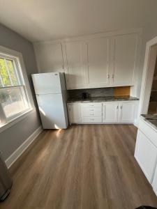 a kitchen with white cabinets and a refrigerator at Beach town bungalow in Sheboygan +4 photos