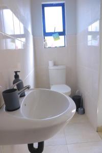 a white bathroom with a sink and a toilet at The Royalty Ebukhosini2 in Teyateyaneng +2 photos