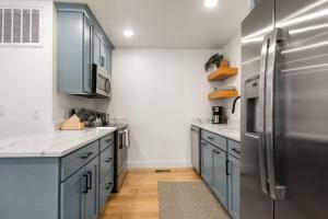 La cuisine est équipée de placards bleus et d'un réfrigérateur en acier inoxydable. dans l'établissement Near Downtown Stylish 2BR With Amazing Patio - 3, à Moab