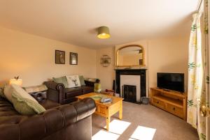 a living room with a couch and a television at Foxglove Cottage in Bransgore