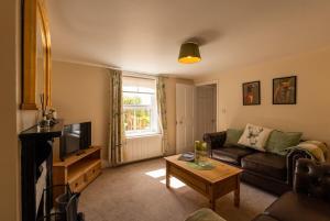 a living room with a couch and a tv at Foxglove Cottage in Bransgore +27 photos