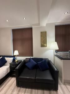 a living room with a black couch and a bed at Stylish Studio Apartment in Leicester