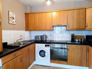 a kitchen with wooden cabinets and a washing machine at City Centre C Apartment, Parking, Ground Floor in Belfast +9 photos