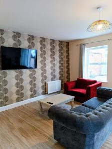 a living room with a couch and a tv on a wall at City Centre C Apartment, Parking, Ground Floor in Belfast