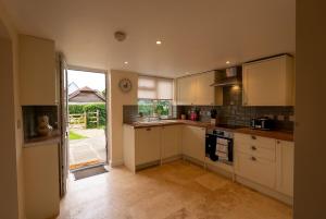 a kitchen with white cabinets and a large window at Rose cottage in Bransgore
