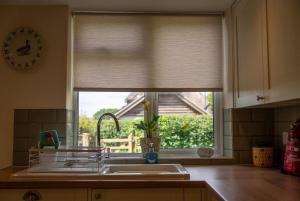 a kitchen sink and a window with a window blind at Rose cottage in Bransgore