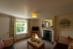 a living room with a couch and a fireplace at Rose cottage in Bransgore