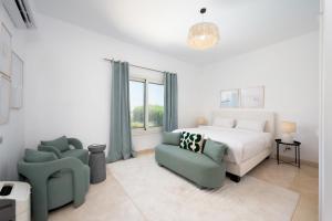 a white bedroom with a bed and two chairs at VESTA - El Gouna Residence in Hurghada +48 photos