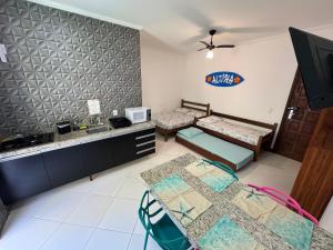 Una sala de estar con dos camas y una cocina. en Apartamentos e Flats da Taty Praia das Toninhas - Ubatuba, en Ubatuba