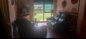 a living room with two leather chairs and a window at Cheroga in La Pedrera +6 photos