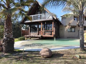 a house with a swimming pool and a palm tree at Cabaña rústica con pileta tipo playa en Salta Capital in Salta