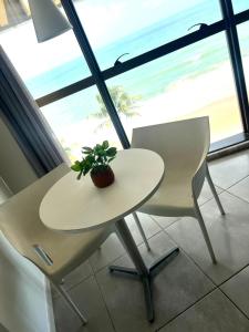 a table and two chairs with a plant on it at Refúgio do Mar 705 - Condomínio Edifício Ritz Suítes Home Service in Maceió