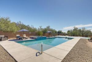 a swimming pool in a yard with chairs and umbrellas at Oro Valley Guest House with Roof Top Views in Oro Valley