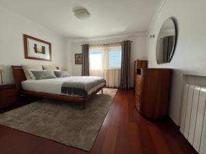 a bedroom with a large bed and a mirror at Vivenda espaçosa com jardim e churrasqueira in Alcabideche