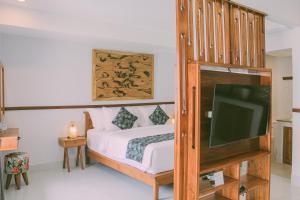 a bedroom with a bed and a flat screen tv at Sejati Villas - Petitenget in Seminyak