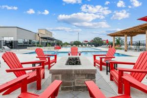 a patio with red chairs and a fire pit with a pool at Luxury Home W Pool & Gym Mins To Baylor Hospital in Marble Falls