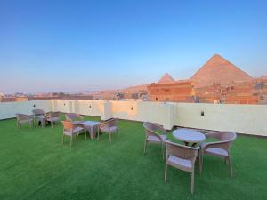a row of tables and chairs on a roof with pyramids at Retaj Pyramids View in Cairo