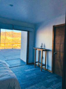 GualliguaicaにあるCasa de Montaña en Puclaro, Valle de Elquiのベッド、テーブル、ドアが備わる部屋