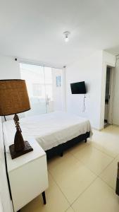 a bedroom with a bed and a table with a lamp at Bahia Bela - Casa Duplex 02 in Santa Cruz Cabrália