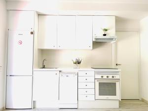 a kitchen with white appliances and white cabinets at Apartamento con piscina y terraza recién reformado in Platja  d'Aro
