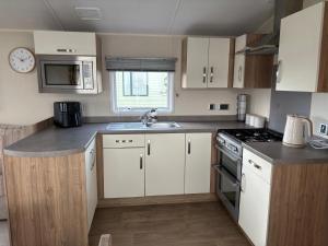 Una pequeña cocina con gabinetes blancos y un fregadero. en Our Happy Place, en Kilkeel