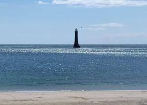 un faro en medio del océano con una playa en Our Happy Place, en Kilkeel
