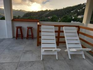 duas cadeiras brancas e dois bancos em uma varanda em Hostal De María em San Cristóbal de Las Casas