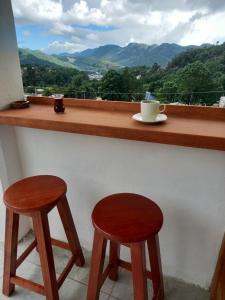 dois bancos de madeira sentados em um bar com vista em Hostal De María em San Cristóbal de Las Casas