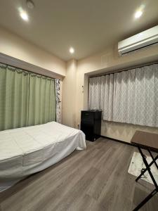 a bedroom with a bed and a desk and a window at 依茶宿 in Matsudo