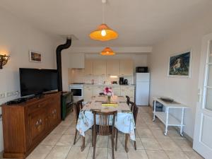a kitchen with a table with chairs and a television at Gîte à la montagne avec cheminée, wifi et joli terrain - FR-1-589-179 in Le Tholy +25 photos