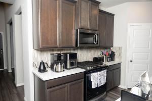 a kitchen with wooden cabinets and a stove and microwave at Private Room in Richmond, TX in Richmond