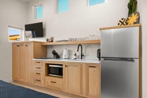 a kitchen with wooden cabinets and a white refrigerator at Downtown Kokopelli West 6 - Newly Remodeled Stylish Studio in Moab