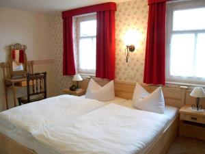a bedroom with a large white bed with red curtains at Holiday home Bauernhauschen in the Rhon in Bernshausen