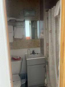 Un baño con lavabo, inodoro y espejo. en Royals Inn Motel, en Malta 3 fotos más