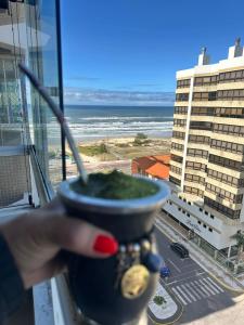 a hand holding a bowl of vegetation in a window at Ap Edifício Sunchine Capão da Canoa RS in Capão da Canoa