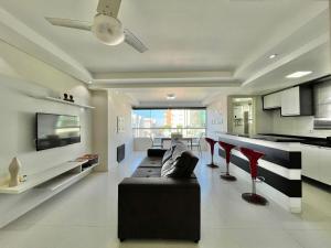 a living room with a black couch and red chairs at Ap Edifício Sunchine Capão da Canoa RS in Capão da Canoa