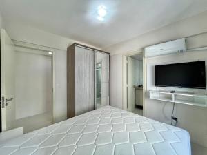 a bedroom with a large white bed and a flat screen tv at Ap Edifício Sunchine Capão da Canoa RS in Capão da Canoa