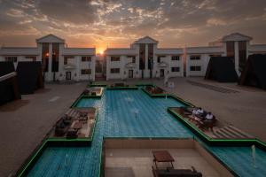 a large swimming pool with people sitting in chairs in front of a building at MidTown Majestic Garden Resort in Abha