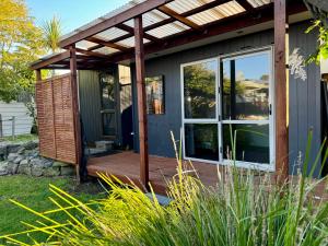 a house with a wooden deck and a pergola at The Kingfisher cabin in Tauranga