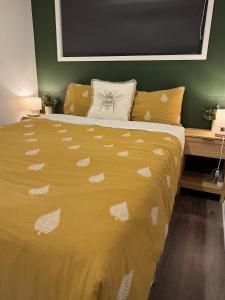 a bed with a yellow comforter with shells on it at The Kingfisher cabin in Tauranga