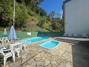a swimming pool with chairs and an umbrella at Surf House Mar Brasil in Ubatuba