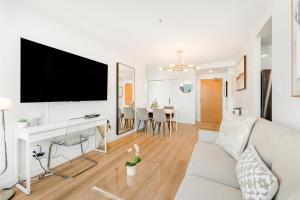 バンクーバーにあるBest Location Downtown Chic Suitesの白いソファと薄型テレビのあるリビングルーム